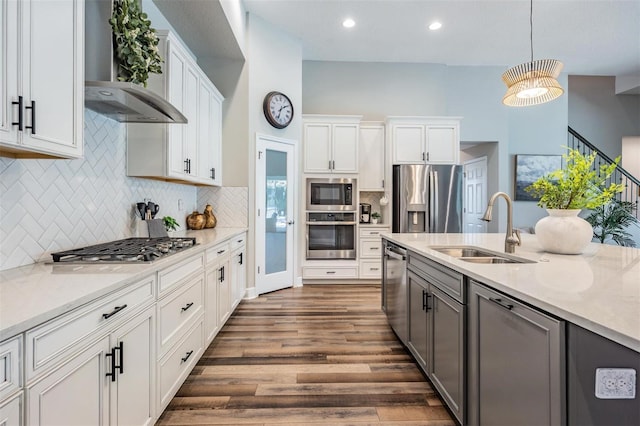 kitchen with wall chimney range hood, a sink, white cabinetry, dark wood finished floors, and appliances with stainless steel finishes
