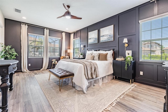 bedroom featuring a decorative wall, a ceiling fan, light wood-type flooring, visible vents, and recessed lighting