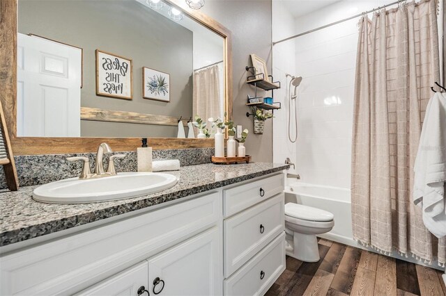 full bath with wood finished floors, shower / tub combo, toilet, and vanity