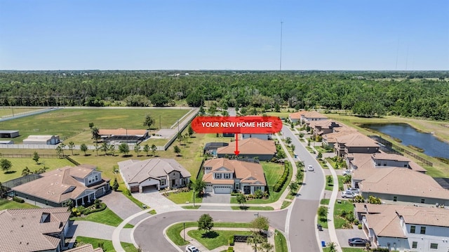 drone / aerial view featuring a wooded view, a residential view, and a water view