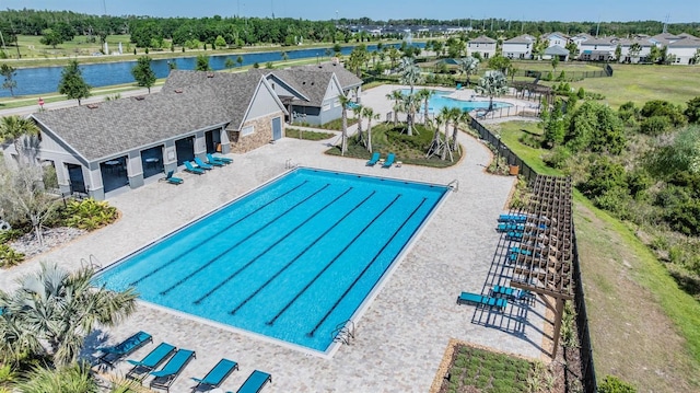 community pool featuring a patio area, a water view, and fence