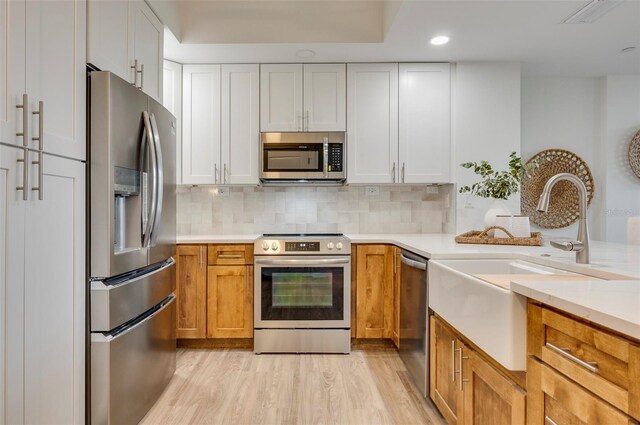 331 Cleveland St Unit 320, Clearwater, FL 33755 - kitchen with light countertops, a sink, light wood finished floors, tasteful backsplash, and appliances with stainless steel finishes