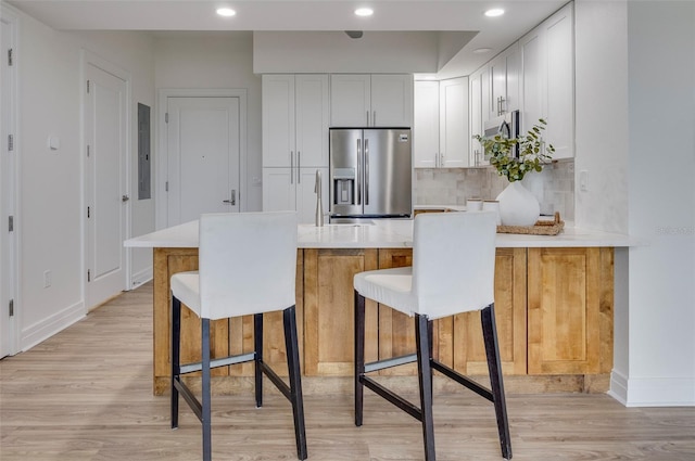 331 Cleveland St Unit 320, Clearwater, FL 33755 - kitchen featuring light countertops, a peninsula, stainless steel appliances, light wood-type flooring, and a kitchen breakfast bar