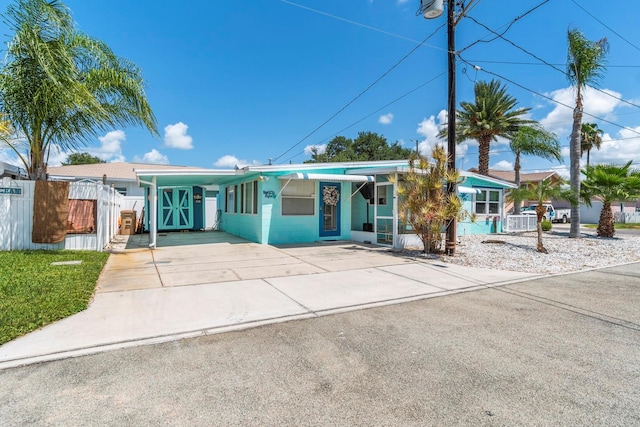 view of front of house featuring driveway, a carport, and fence