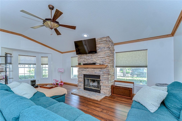 living room featuring a stone fireplace, crown molding, a ceiling fan, hardwood / wood-style floors, and lofted ceiling