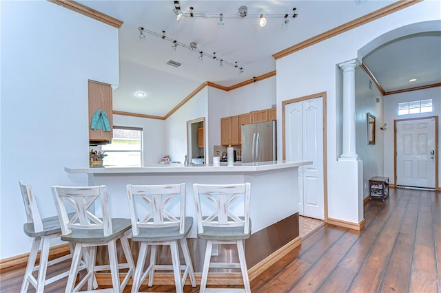 kitchen featuring crown molding, freestanding refrigerator, a kitchen bar, ornate columns, and hardwood / wood-style floors