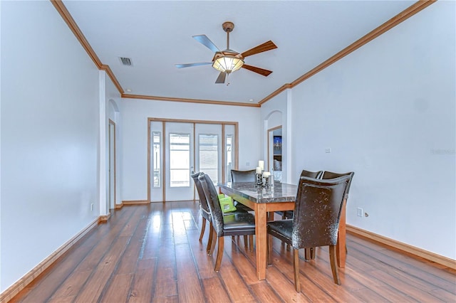 dining area with arched walkways, visible vents, baseboards, and wood finished floors