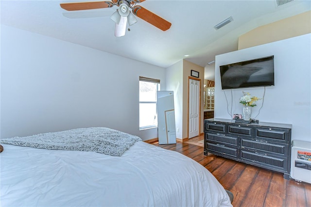 bedroom featuring vaulted ceiling, a ceiling fan, heating unit, visible vents, and wood finished floors