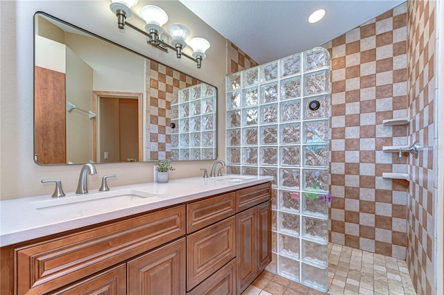 bathroom featuring a walk in shower, double vanity, and a sink