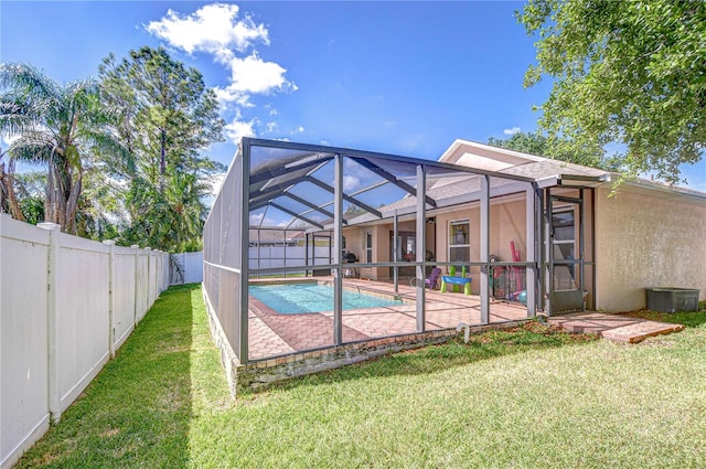 view of swimming pool with a fenced in pool, a patio area, a fenced backyard, a yard, and glass enclosure