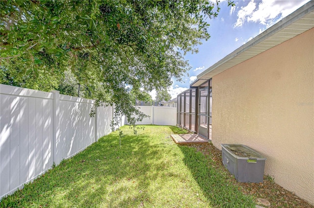 view of yard featuring a fenced backyard and glass enclosure