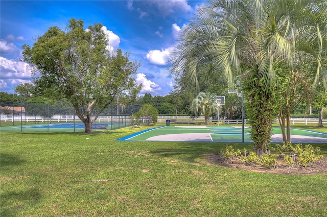 view of basketball court featuring community basketball court, a tennis court, fence, and a lawn