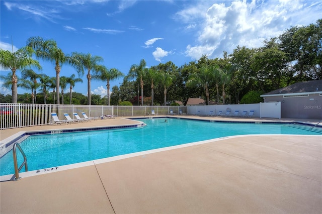 community pool with a patio area and fence