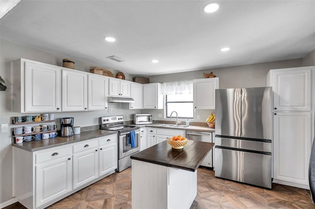 13308 Kearney Way, Tampa, FL 33626 - kitchen with white cabinetry, appliances with stainless steel finishes, under cabinet range hood, dark countertops, and a sink