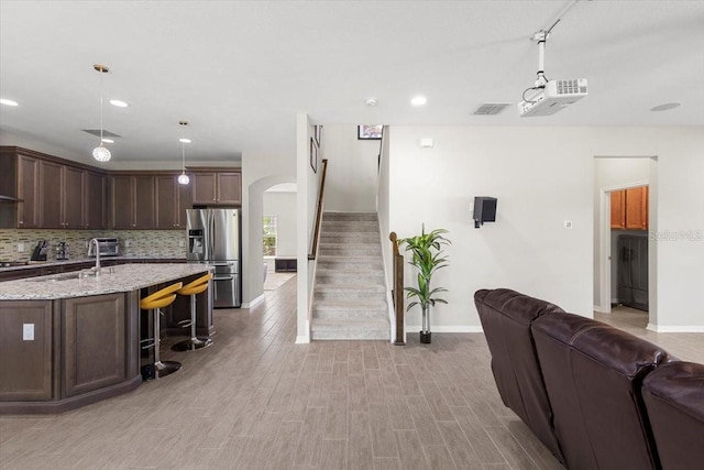 interior space featuring arched walkways, light wood-type flooring, baseboards, and stairs