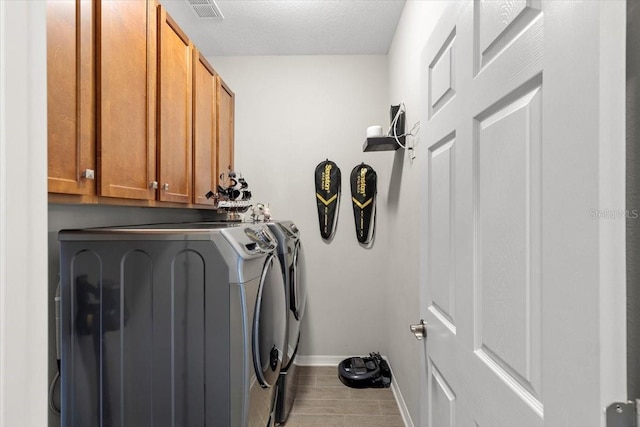 laundry area with baseboards, washing machine and dryer, a textured ceiling, visible vents, and cabinet space