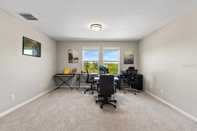 carpeted home office featuring visible vents, baseboards, and a textured ceiling