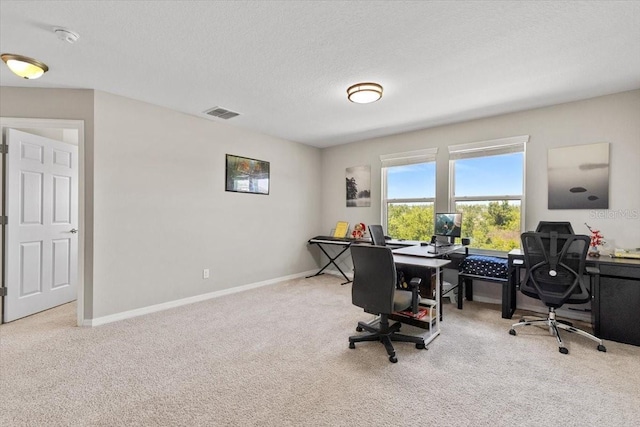 carpeted office with visible vents, baseboards, and a textured ceiling