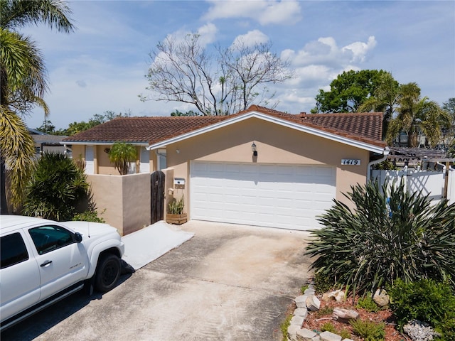 view of front of house featuring stucco siding, an attached garage, fence, and concrete driveway
