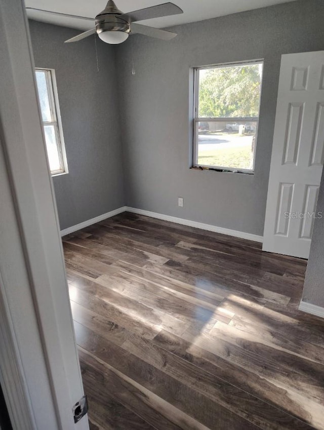 unfurnished room with ceiling fan, baseboards, and dark wood-style floors