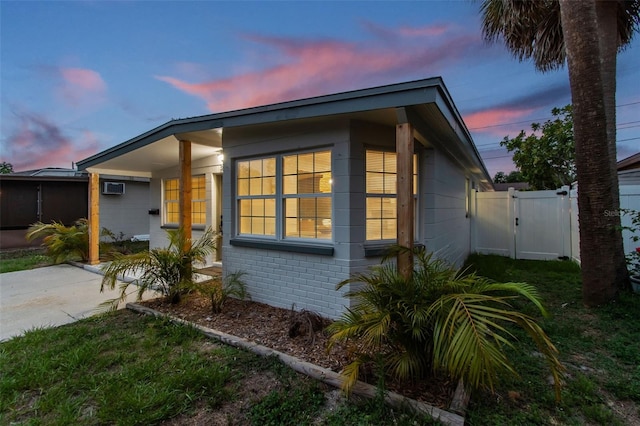 3066 Highland St N, Saint Petersburg, FL 33704 - property exterior at dusk featuring a gate, brick siding, and an AC wall unit