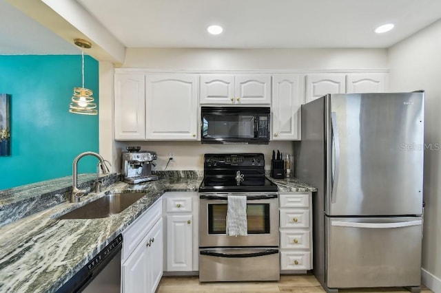 kitchen featuring a sink, appliances with stainless steel finishes, white cabinetry, dark stone counters, and pendant lighting