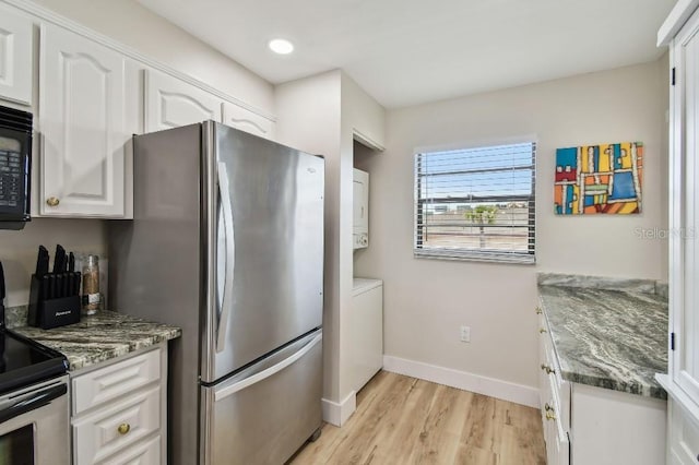 kitchen with dark stone countertops, appliances with stainless steel finishes, light wood finished floors, and white cabinetry