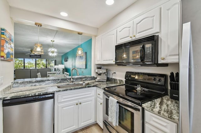 kitchen featuring white cabinets, dark stone counters, appliances with stainless steel finishes, pendant lighting, and a sink