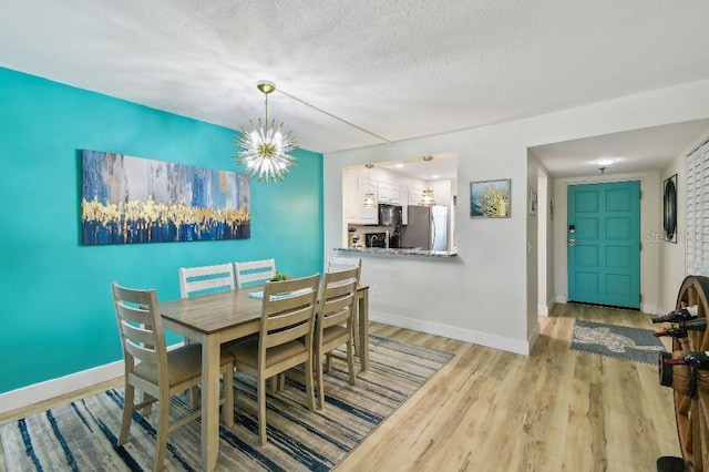 dining space with a textured ceiling, wood finished floors, baseboards, and a notable chandelier