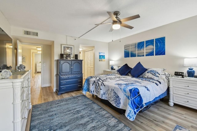 bedroom featuring a closet, light wood finished floors, ceiling fan, and visible vents