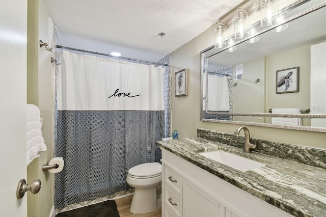 bathroom with vanity, curtained shower, a textured ceiling, toilet, and wood finished floors