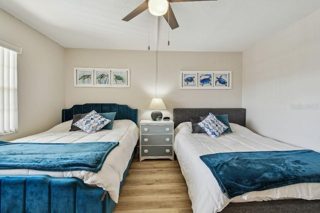 bedroom featuring ceiling fan, multiple windows, and wood finished floors