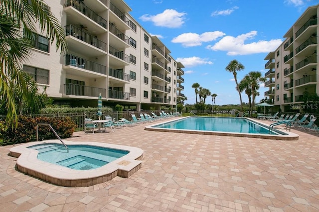 pool featuring a community hot tub, a patio area, and fence