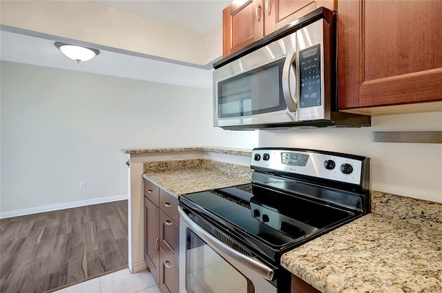 3206 W Azeele St Unit 126, Tampa, FL 33609 - kitchen with appliances with stainless steel finishes, light stone counters, baseboards, and brown cabinetry