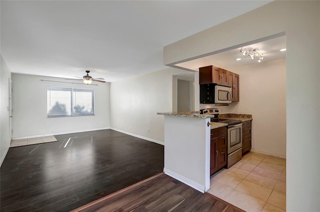 3206 W Azeele St Unit 126, Tampa, FL 33609 - kitchen with stainless steel appliances, a ceiling fan, light stone counters, light wood-style flooring, and baseboards