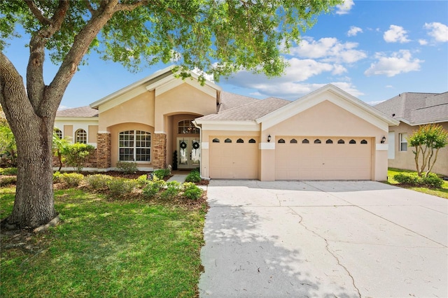 view of front of home featuring stucco siding, a garage, french doors, and concrete driveway