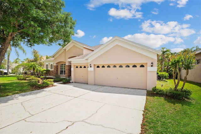 view of front of home featuring a garage, concrete driveway, stucco siding, and a front lawn
