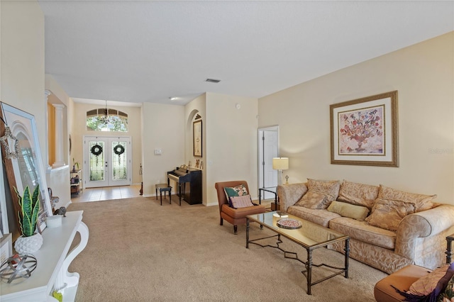 carpeted living area with baseboards, visible vents, french doors, and tile patterned floors