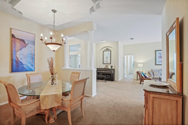 dining room featuring a chandelier, baseboards, light colored carpet, visible vents, and ornate columns