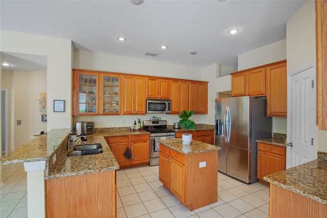 kitchen with visible vents, a peninsula, appliances with stainless steel finishes, a sink, and light stone counters
