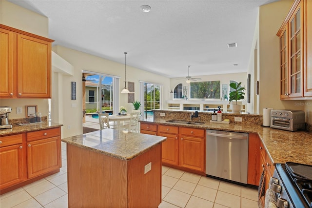 kitchen featuring stainless steel appliances, a sink, ceiling fan, visible vents, and brown cabinets
