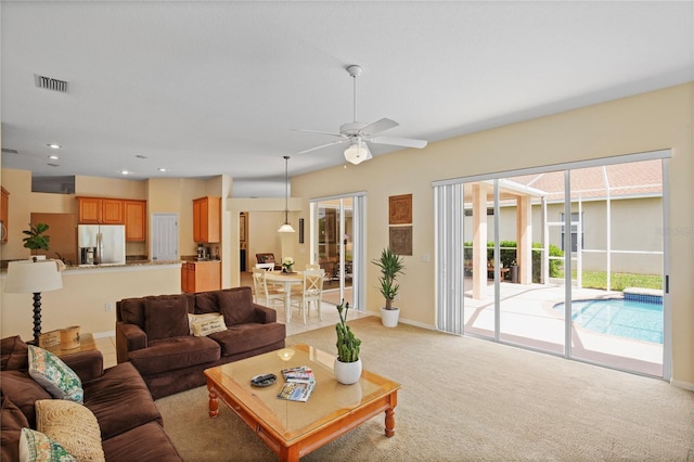 living area featuring visible vents, baseboards, ceiling fan, recessed lighting, and light colored carpet