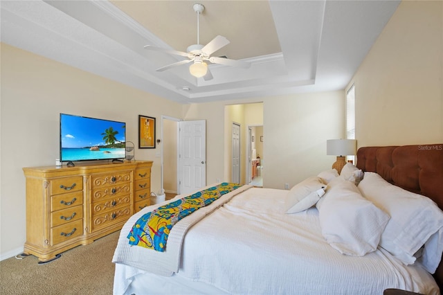 carpeted bedroom featuring baseboards, ceiling fan, ensuite bathroom, and a raised ceiling