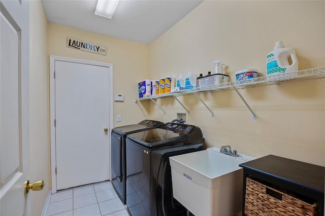 clothes washing area featuring separate washer and dryer, a sink, light tile patterned floors, and laundry area