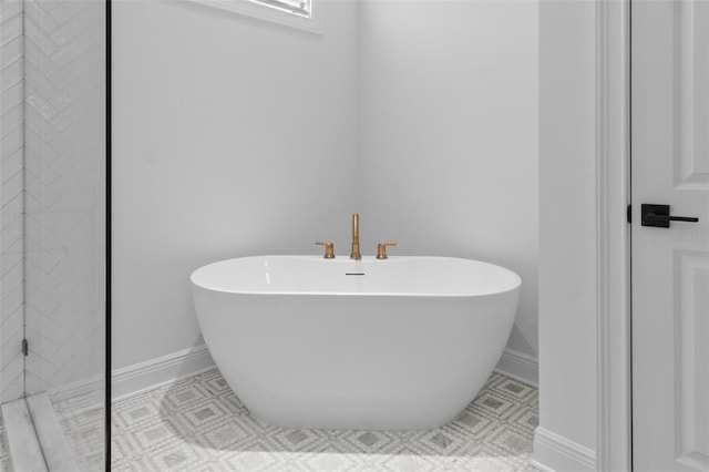 bathroom featuring a freestanding tub, baseboards, and tile patterned floors