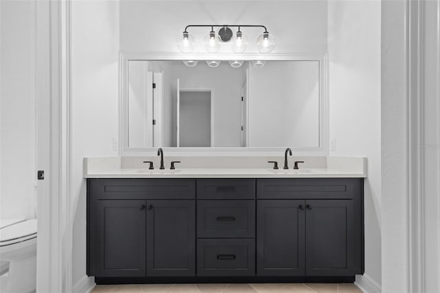 full bath with toilet, double vanity, baseboards, and tile patterned flooring