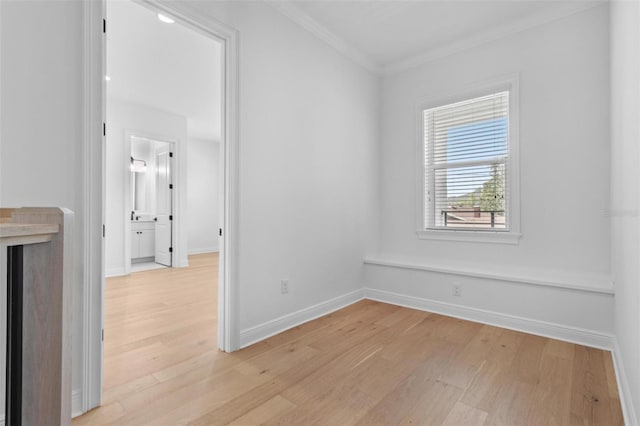 unfurnished room featuring light wood finished floors, ornamental molding, and baseboards