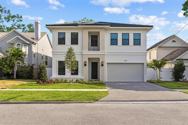 view of front of house featuring decorative driveway, an attached garage, a front yard, and stucco siding
