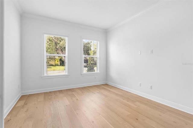 empty room with light wood-style flooring, crown molding, and baseboards
