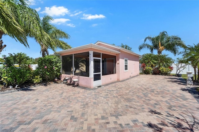 rear view of house with a sunroom and stucco siding